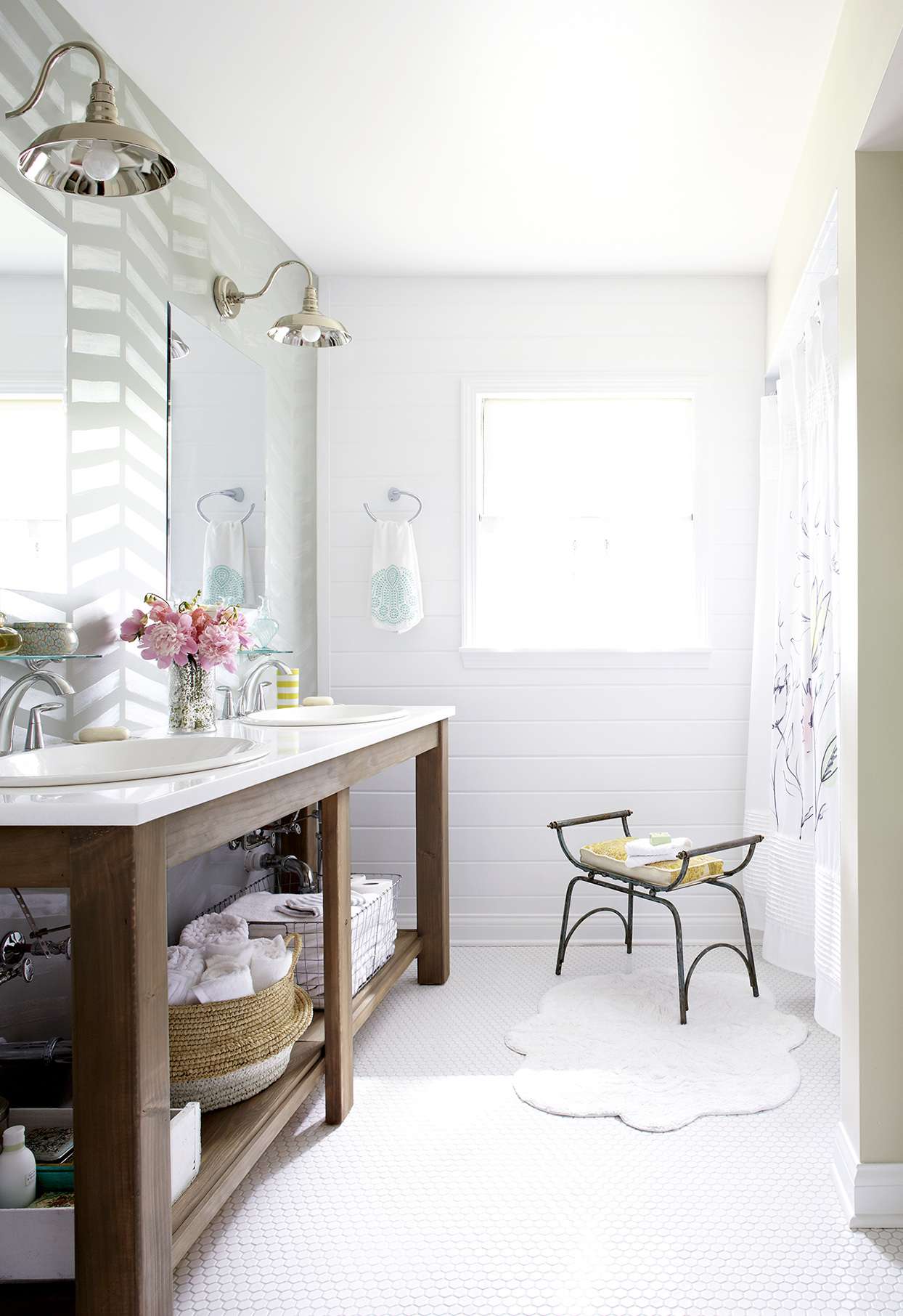 white bathroom with wooden double vanity and small bench