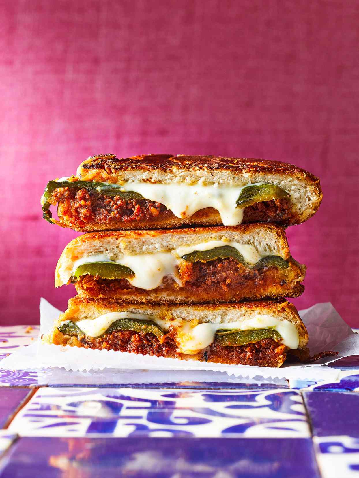 stack of three cut sandwiches with cheese, peppers, and chorizo