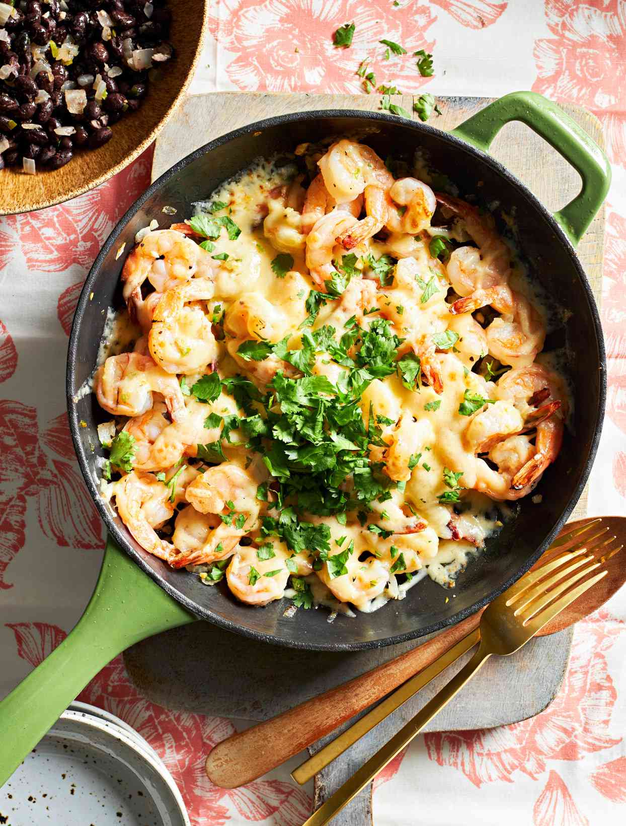 cast iron skillet with shrimp topped with cheese and cilantro