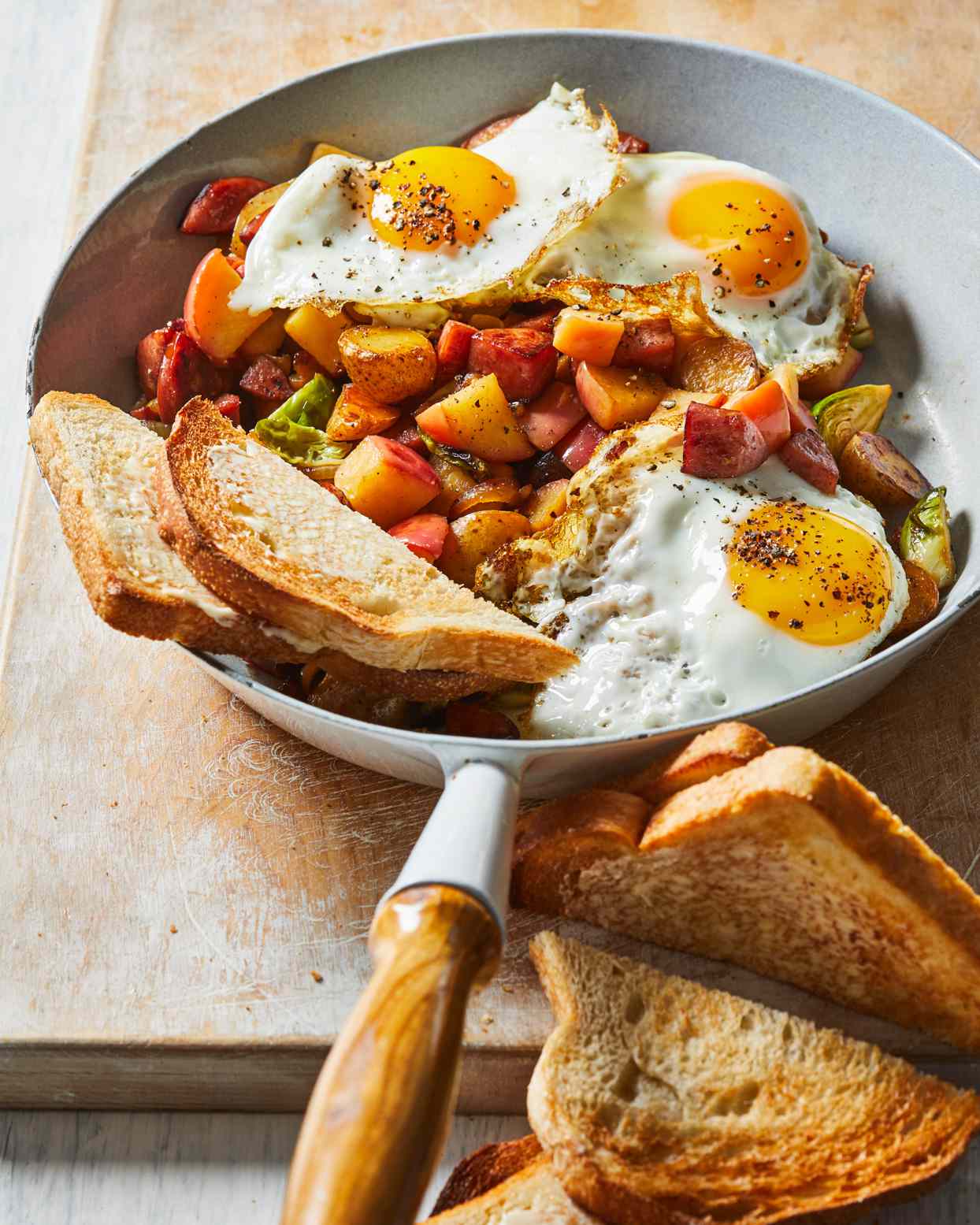 Apple-Kielbasa Hash in skillet topped with 3 fried eggs and toast