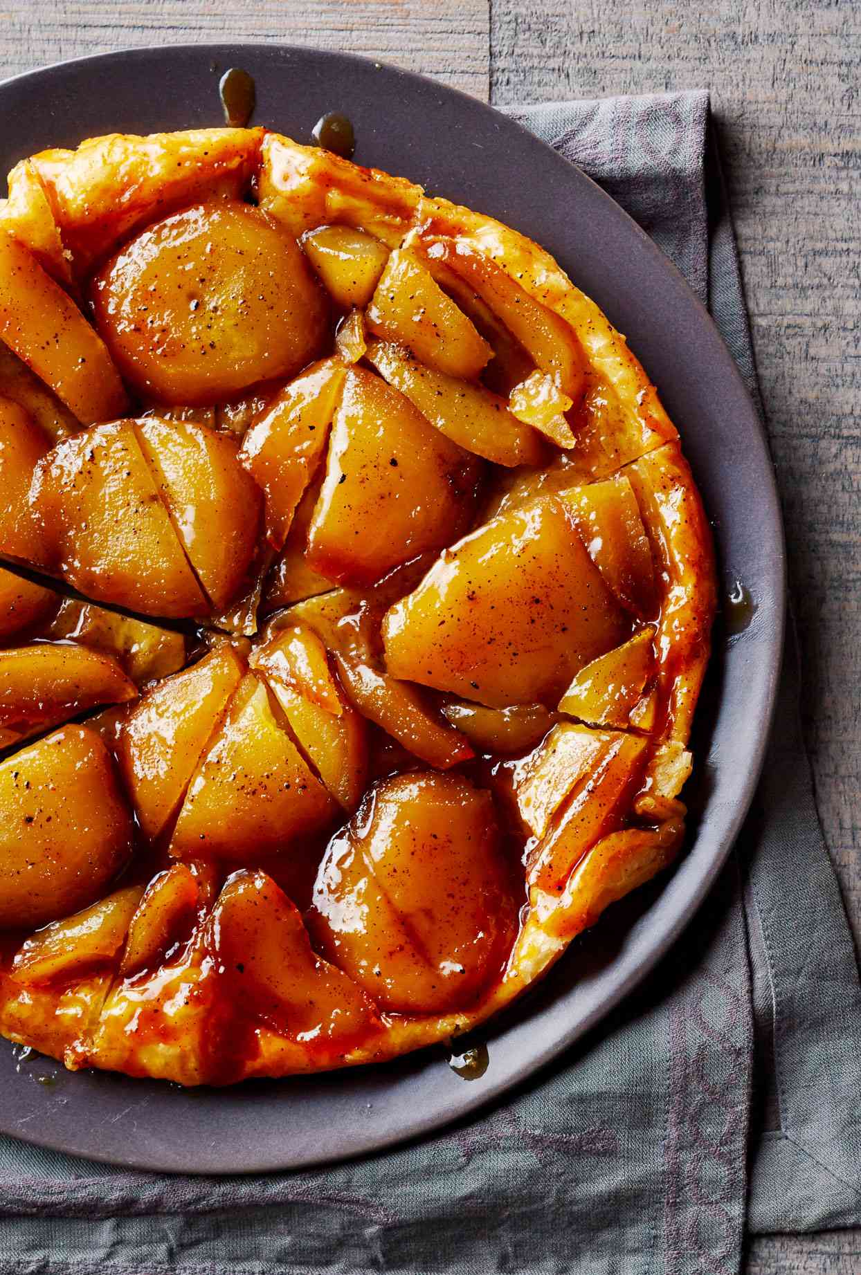 Tart with large pieces of baked apples on black plate