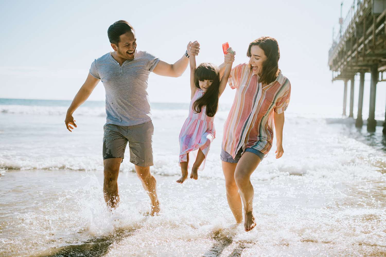 happy family of three playing in the water at a California beach