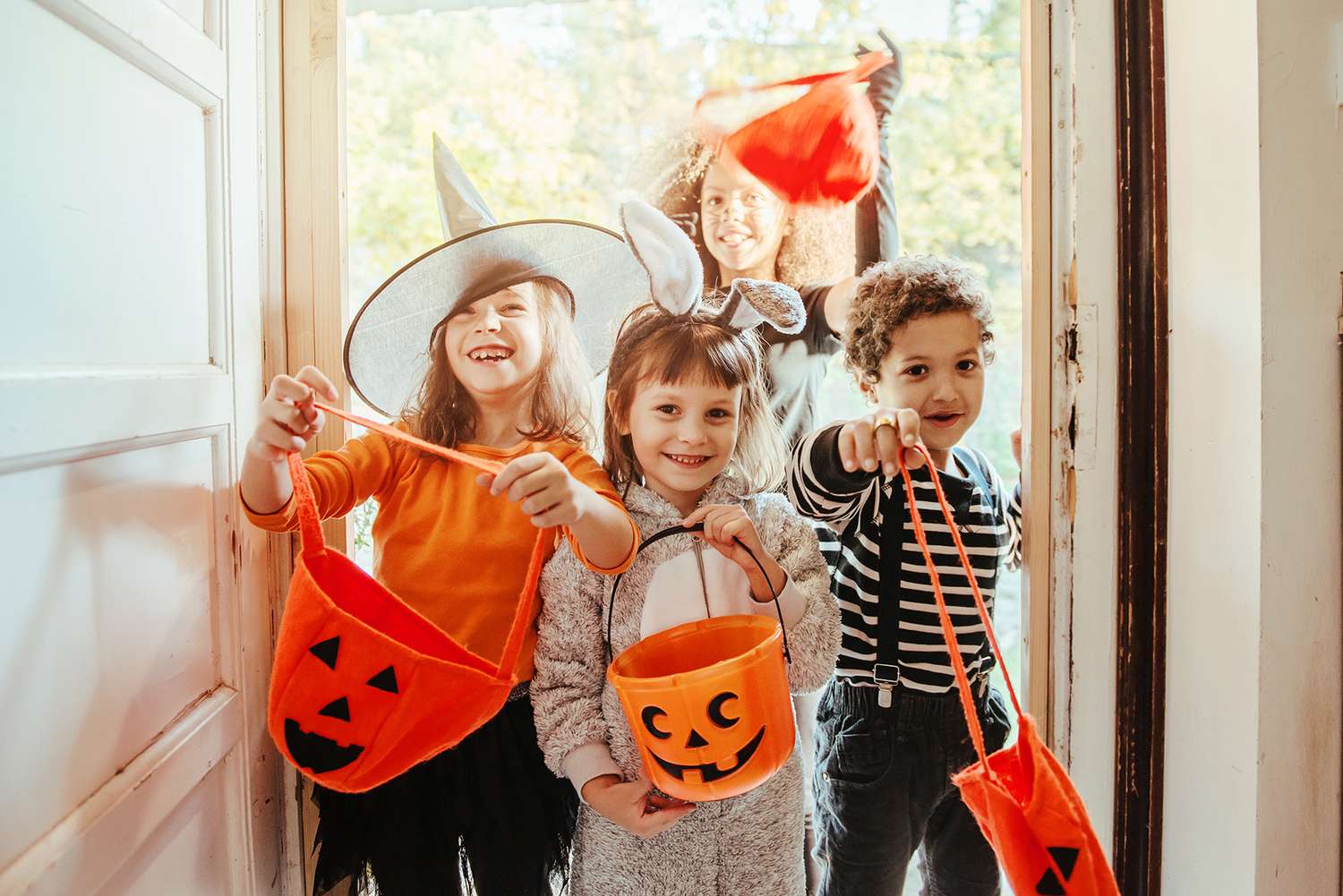 kids with pumpkin buckets trick or treating at front door