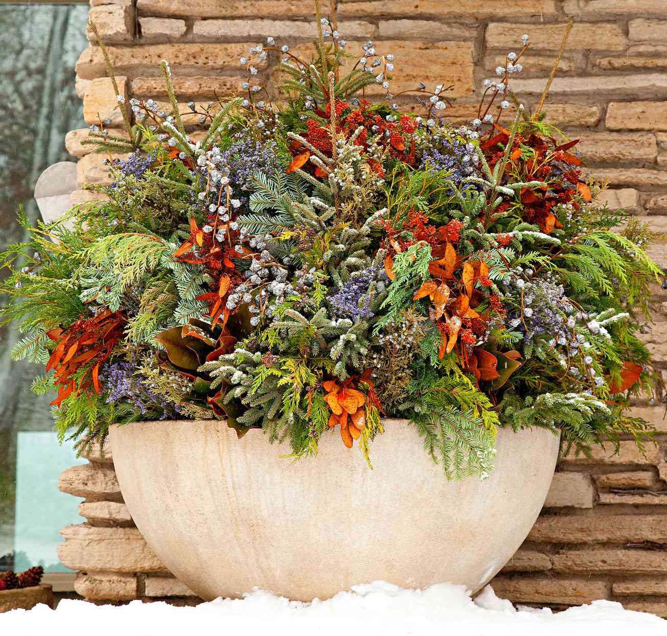 round planter with evergreens and dried perennials