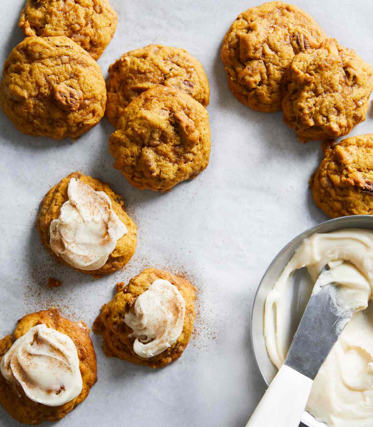 pumpkin cookies topped with frosting on a marble gray background
