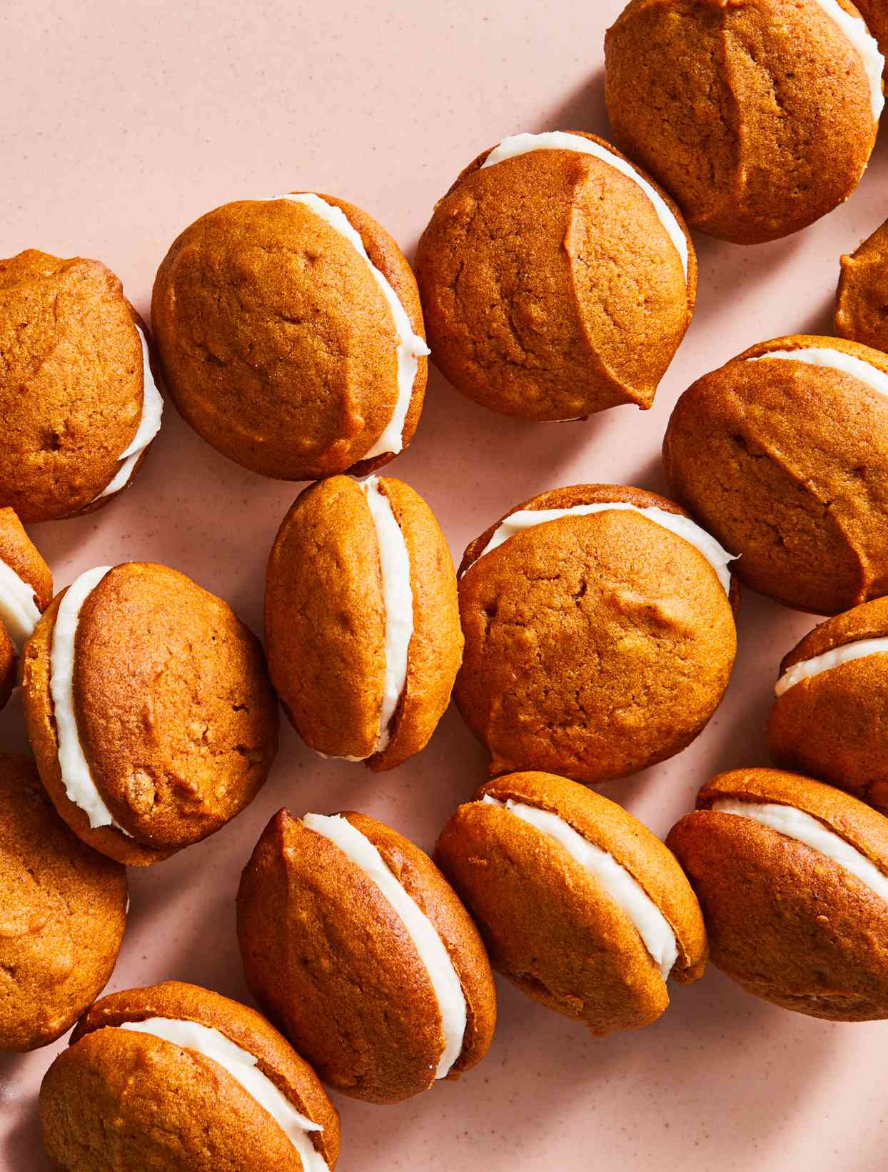Mini Pumpkin Whoopie Pies spread out on light pink background