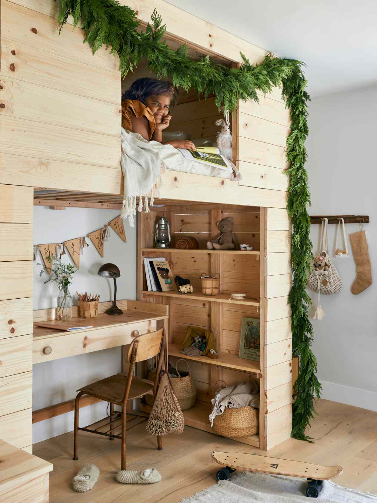 kid in wooden bunk bed with greenery garland