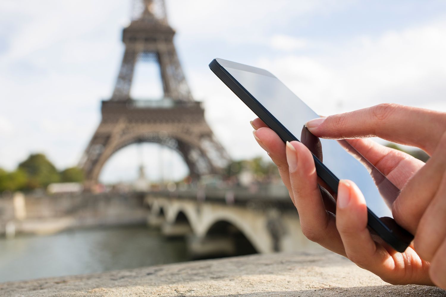 person using an smart phone in front of the Eiffel Tower