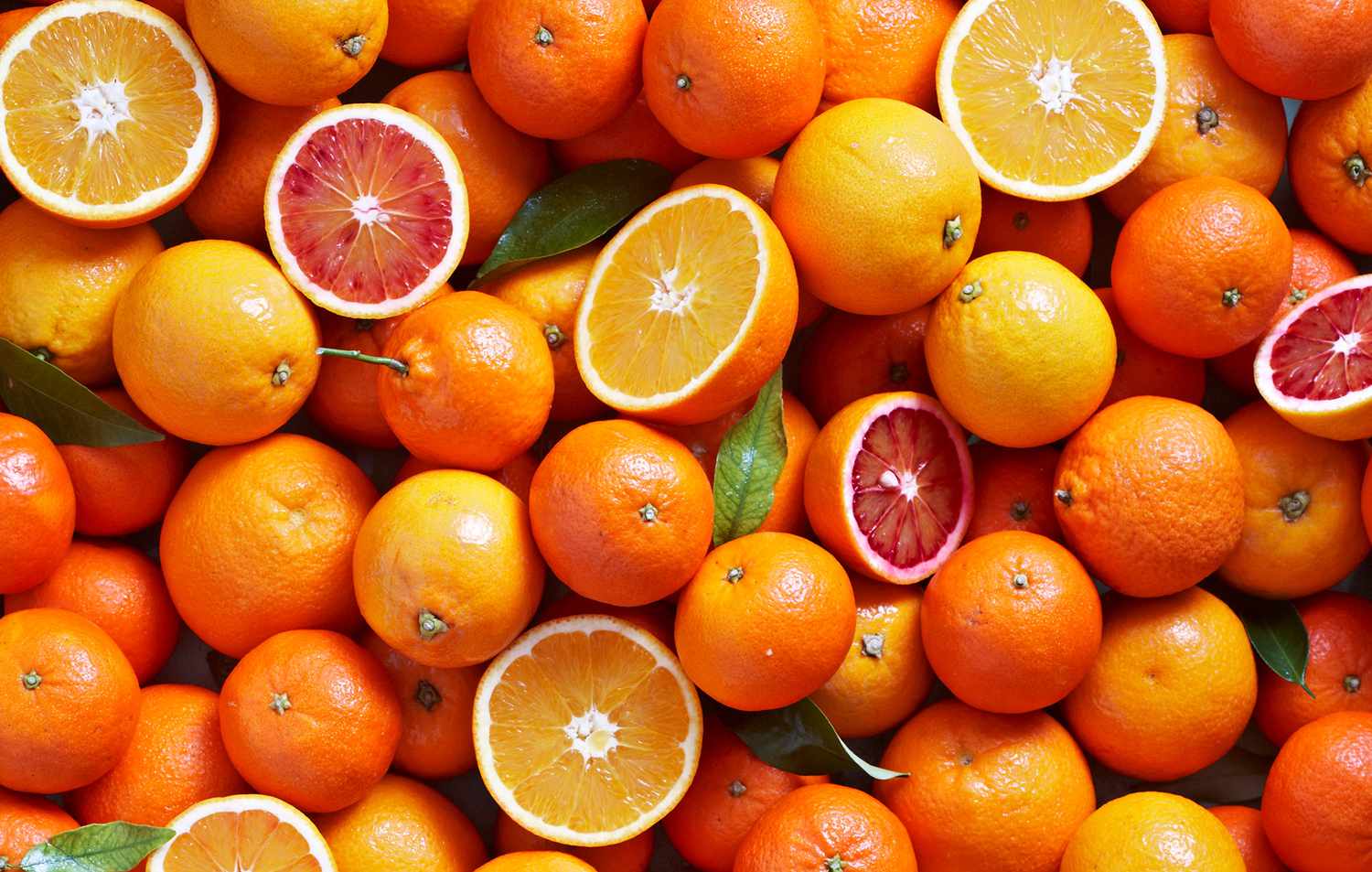 different types of oranges such as blood orange, mandarins and naval oranges overhead with some sliced open
