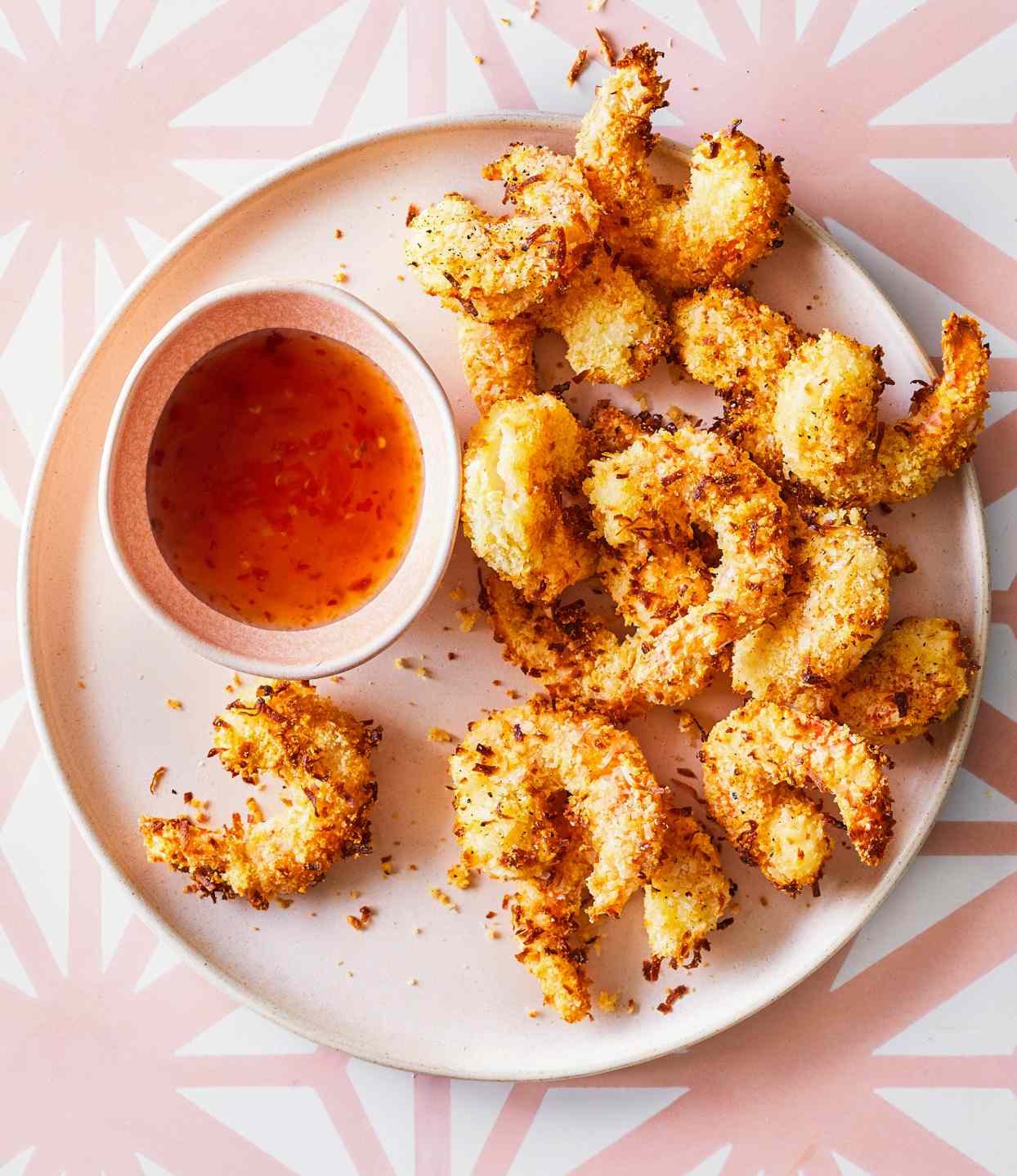 coconut shrimp on white plate with cup of dipping sauce
