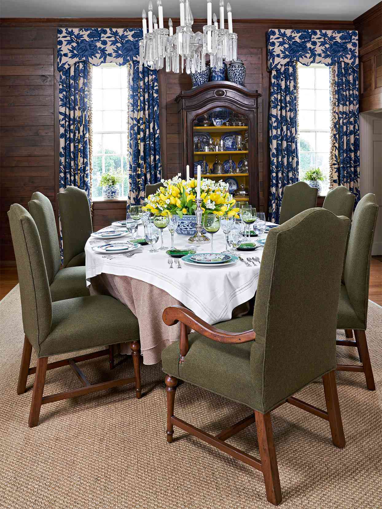 traditional dining room wood paneled walls green chairs yellow centerpiece