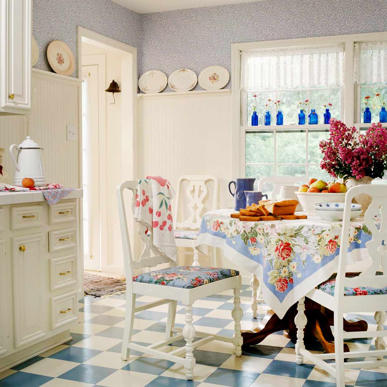 1995 white Provencel inspired kitchen with all white chairs and floral tablecloth