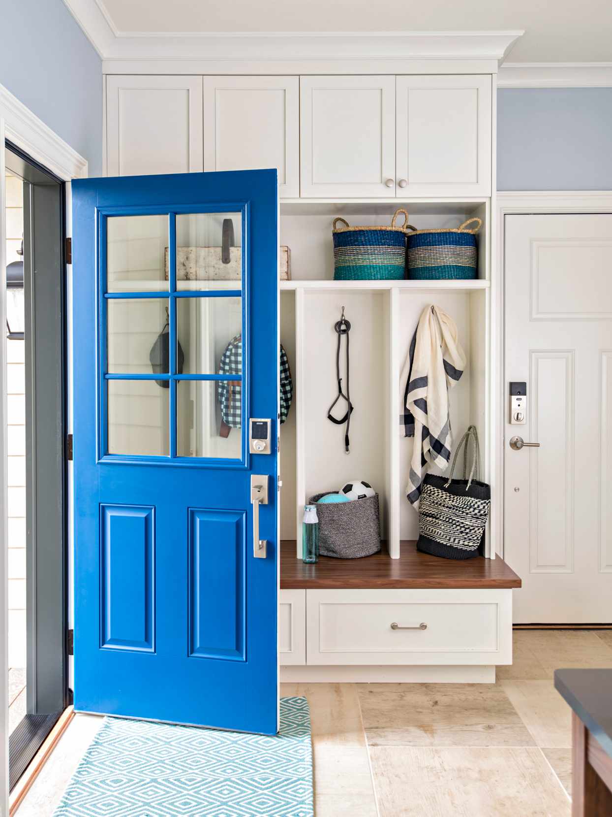 bright blue door open to entryway with storage insert