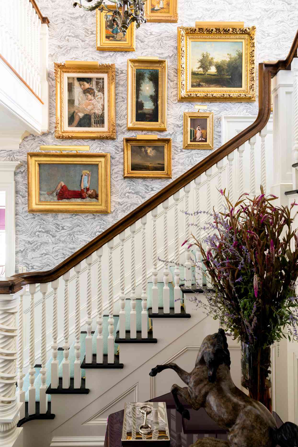 artwork leading up the stairs in gold frames