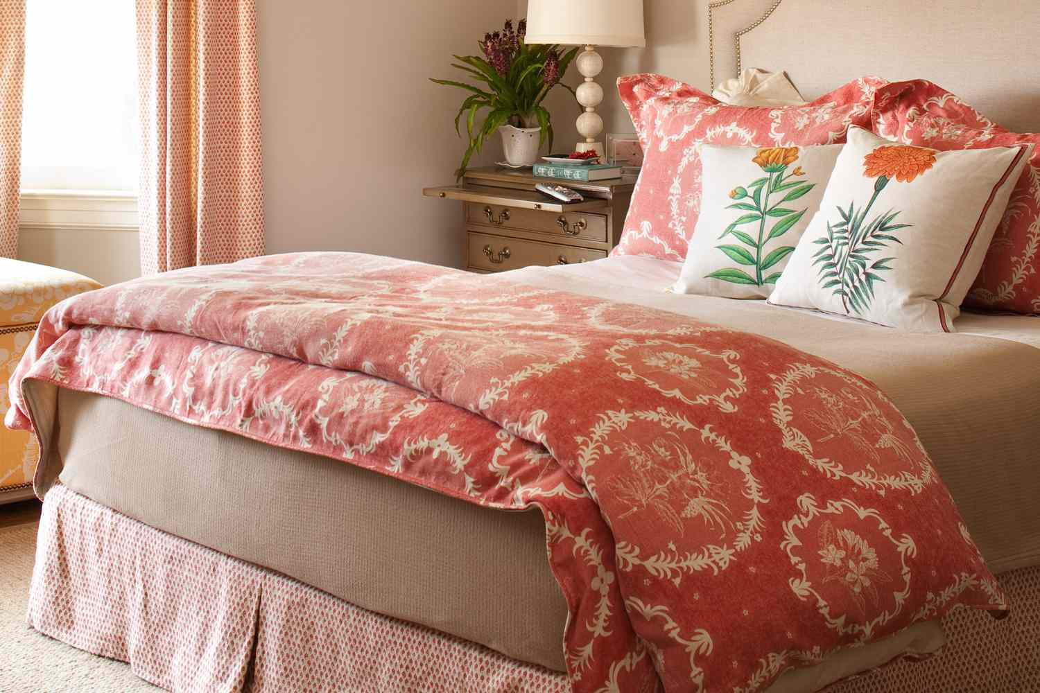 neatly made bed in bedroom with red pink duvet cover