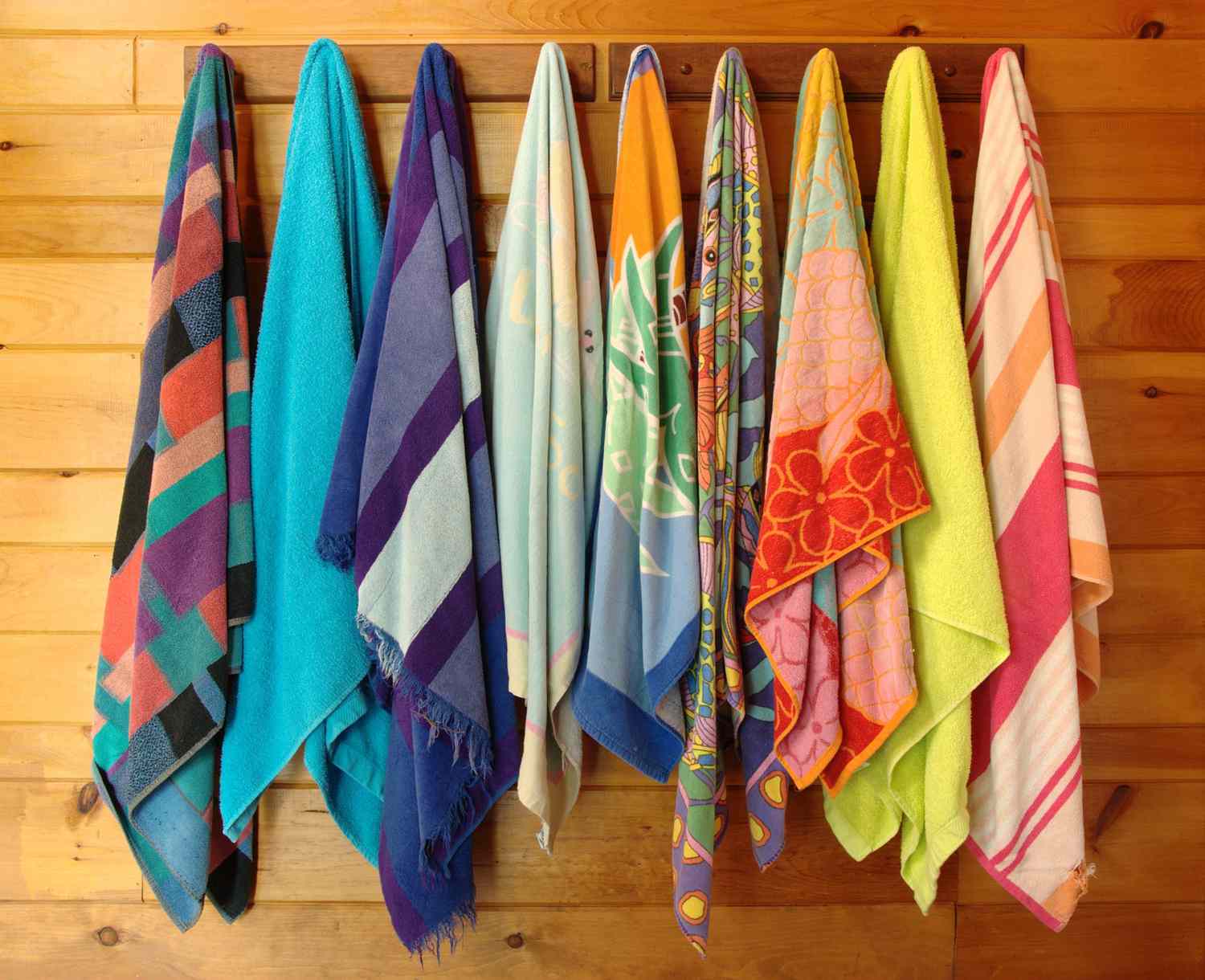 Row of colorful beach towels hanging on hooks