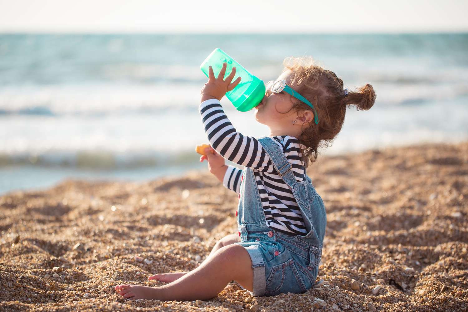 baby drinking from bottle at beach