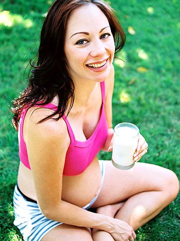 pregnant in pink half-top at park drinking milk