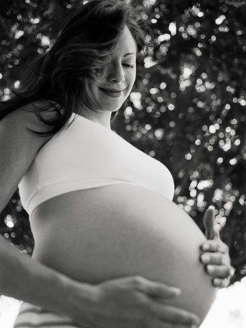 Black and white of pregnant mom with hands on belly, smiling