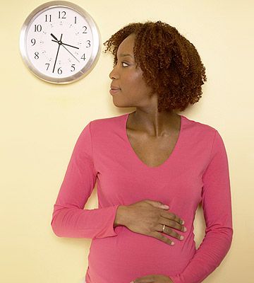pregnant woman looking at clock