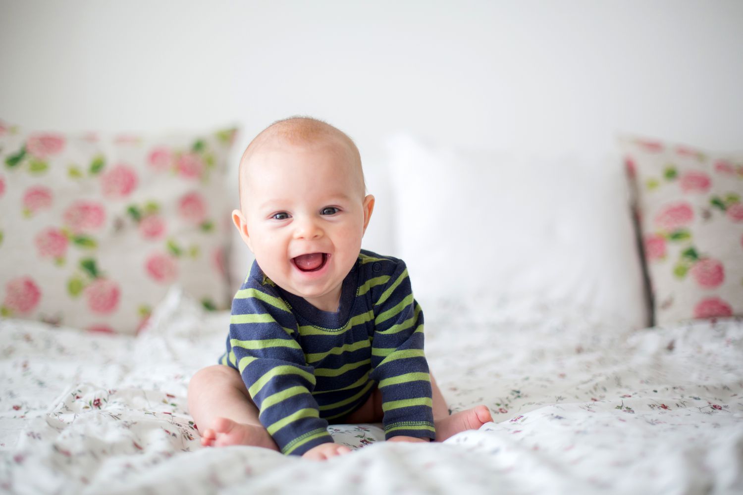 happy baby sitting on bed
