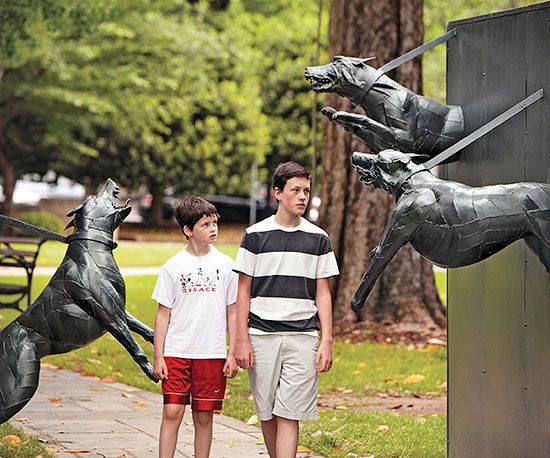 Boys walking between dog statues