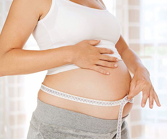 Pregnant woman measuring her stomach