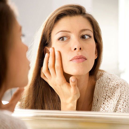 woman checking out her skin in mirror