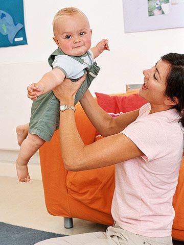 woman holding baby in air