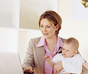 woman on computer holding baby