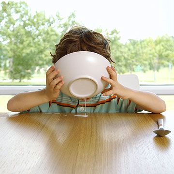 child drinking milk out of bowl