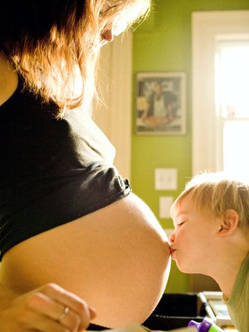 children kissing mom's pregnant belly