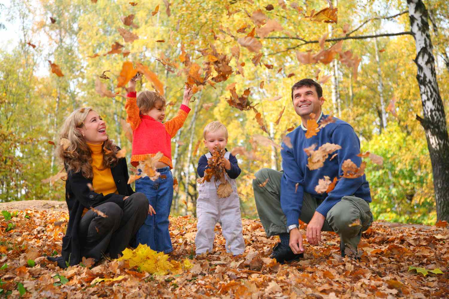 family playing in fall leaves