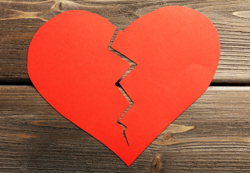 Broken red paper heart on wood background