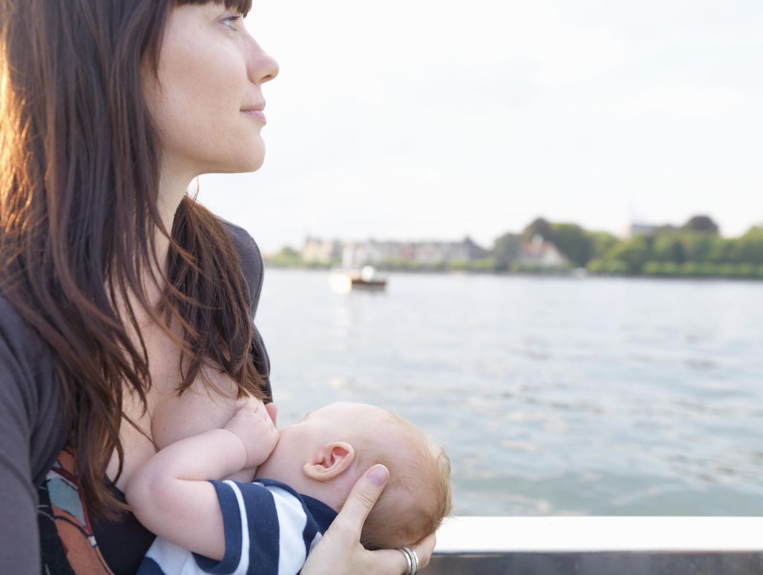 Woman breastfeeding baby near the water
