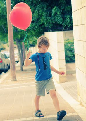 Autistic boy holding a red balloon