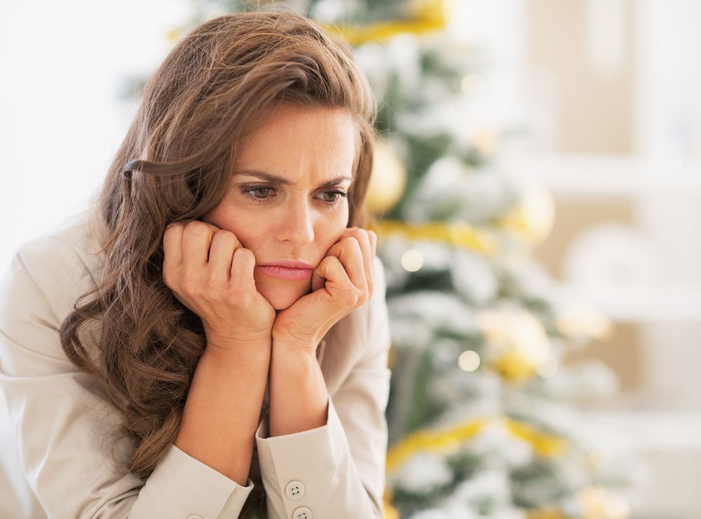 Upset Woman Sitting in Front pf Christmas Tree