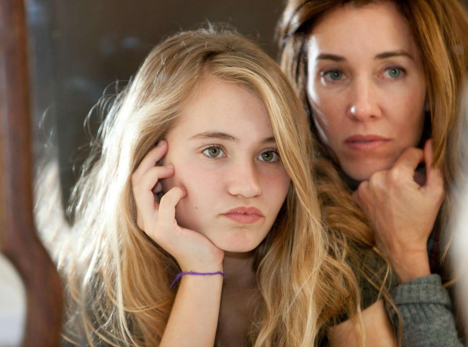 Mother and preteen daughter looking in mirror