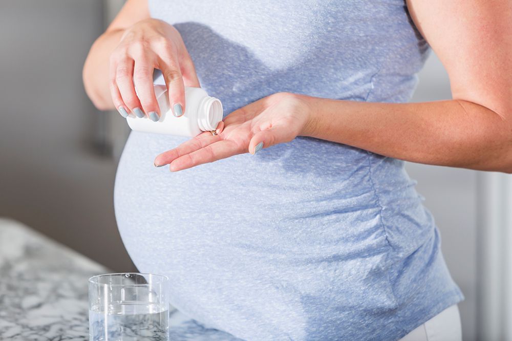 pregnant woman taking a pill