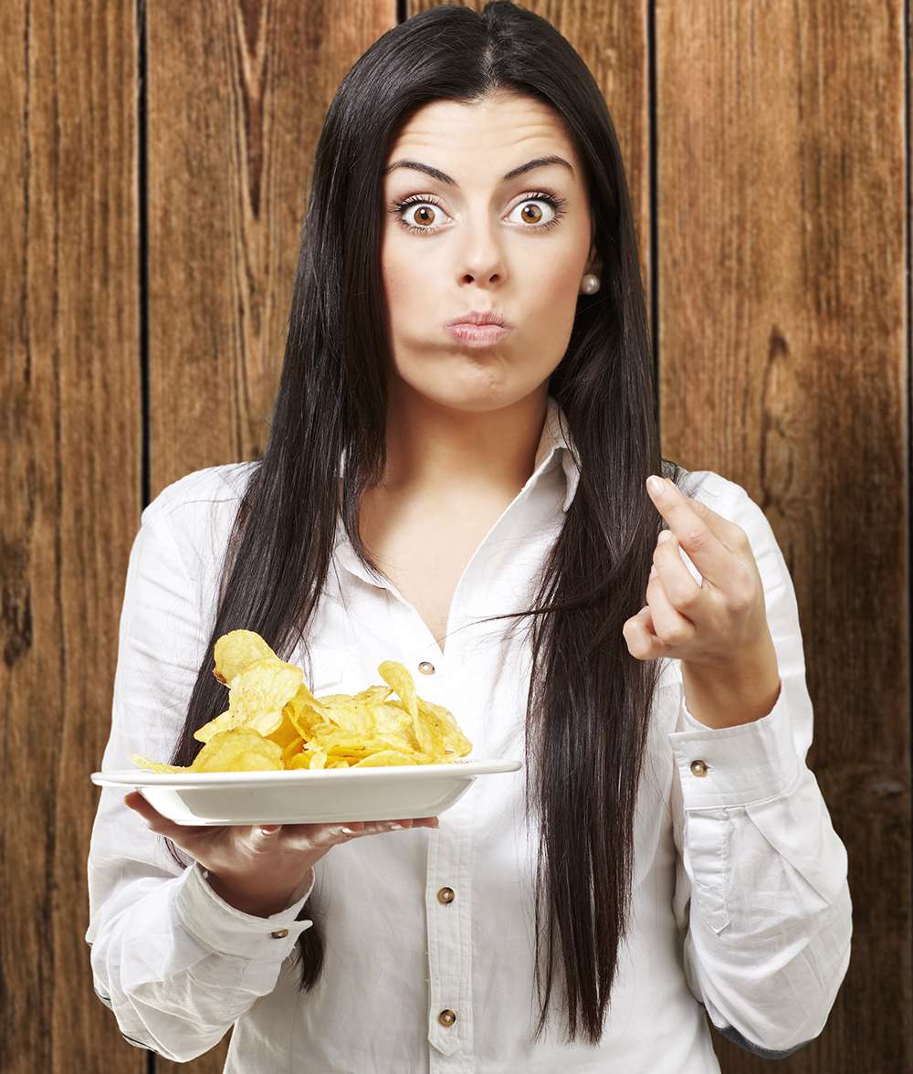surprised woman eating plate of potato chips