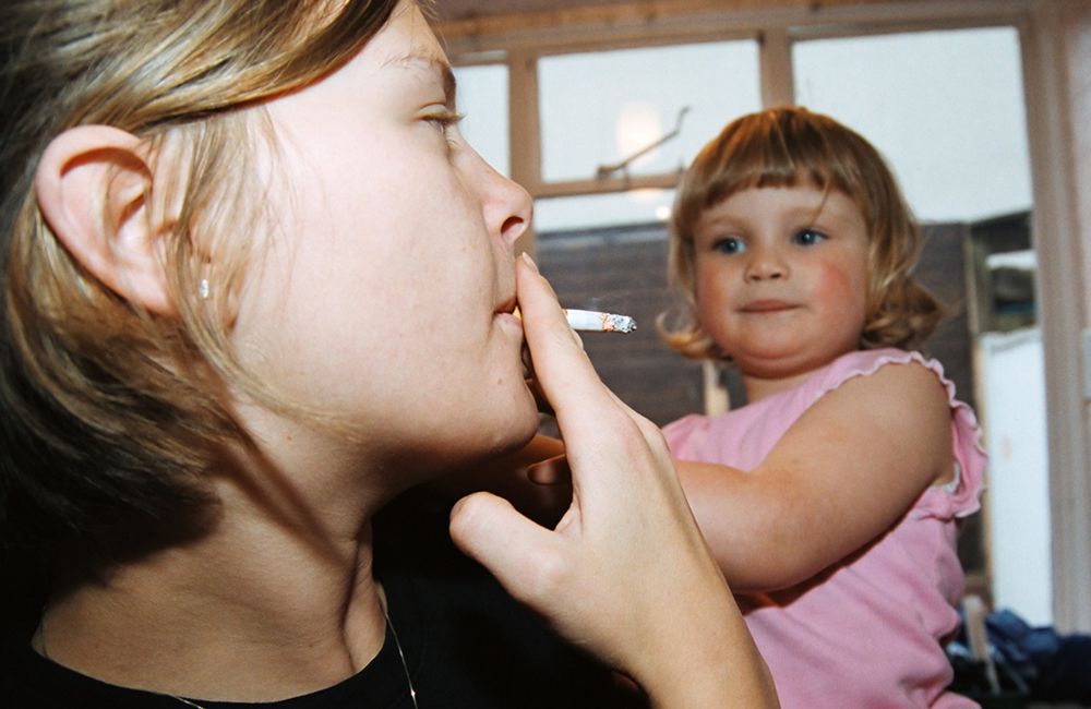 mom smoking while holding daughter