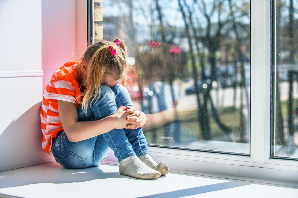 little girl crying on a window sill