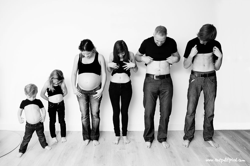 parents and kids looking at bare bellies as pregnancy announcement photo idea
