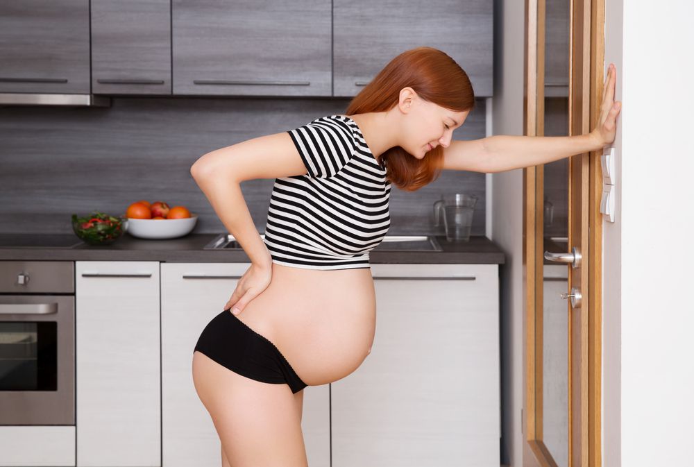 Pregnant woman wearing striped top in labor, holding back