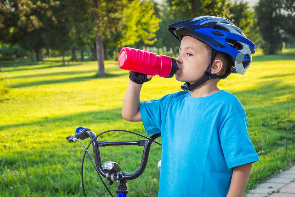 Boy in Helmet Drinking from a Bottle
