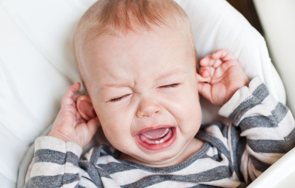 baby crying and holding ears