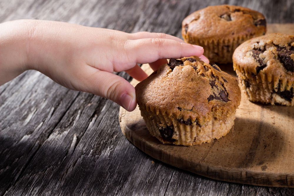 Child Reaching for Second Helping of Muffins