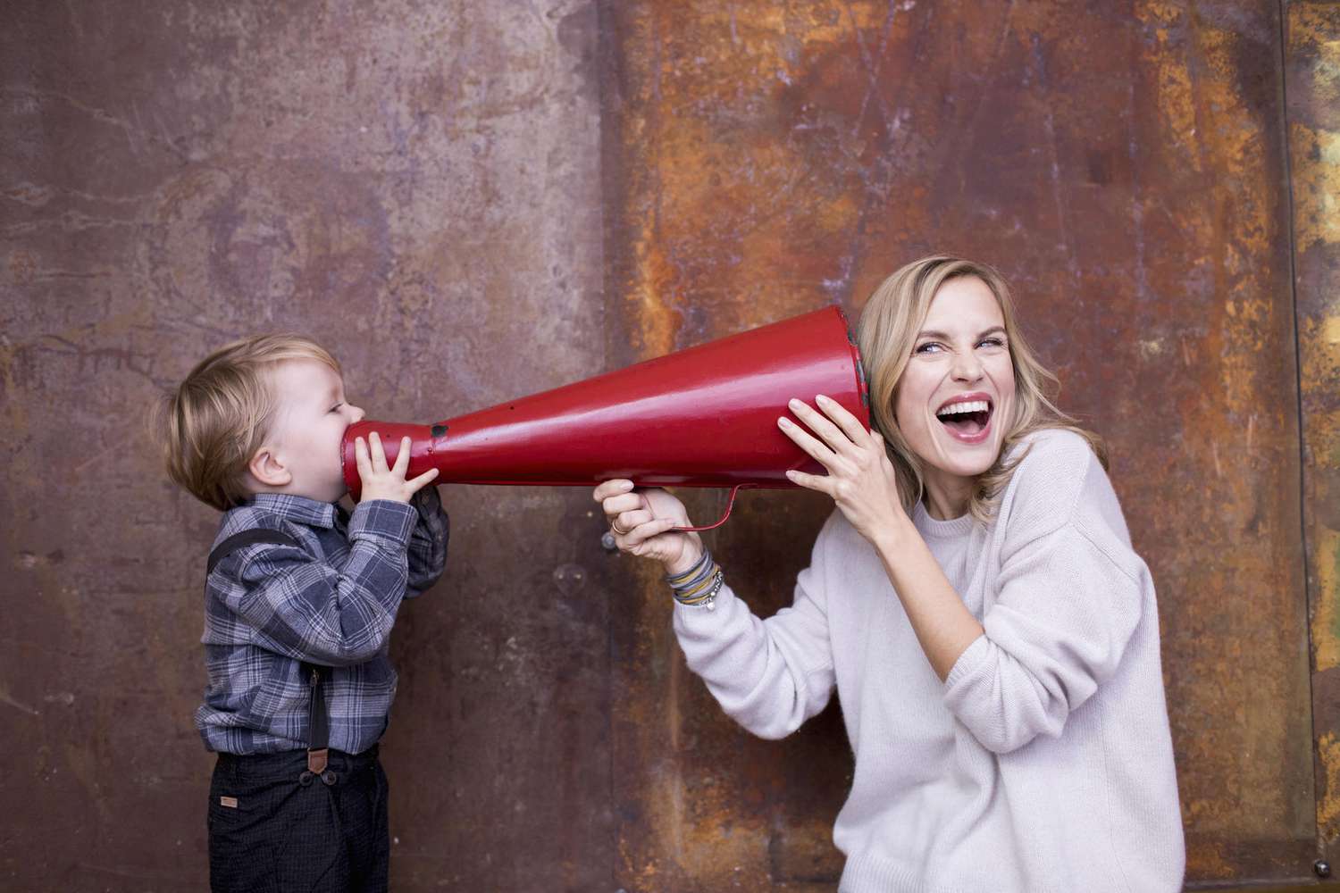Young boy speaking into megaphone, woman holding megaphone to her ear