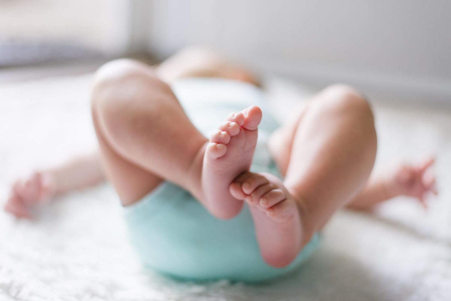Baby Laying Down Tiny Feet Blue Onesie