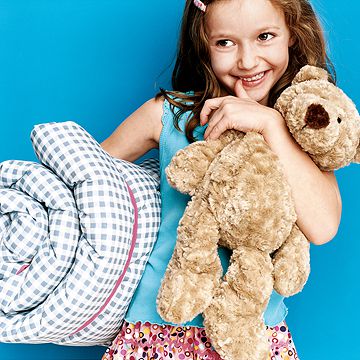 girl holding her bear and sleeping bag